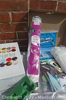 Photo showing a box of assorted colored threads, packages of material sheets, and bobbins on a surface.