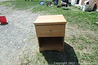 Front view of the maple bedside table showing the drawer and open shelf.