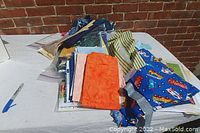 Photo of assorted new sewing fabrics including children’s design fabric with vehicles and various solid and patterned fabric pieces on table.