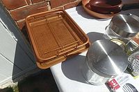 Metal serving grill rack placed on table alongside other kitchen items including glass jars with metal lids and brown cookware.