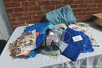 Assorted sewing materials and fabrics laid out on a table in natural light, showing various fabric pieces and some sewing accessories