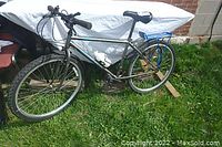 Side view of Norco Mountaineer SL mountain bike with black frame and blue rear rack, outdoors on grass.