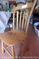 Side view of solid oak chair showing curved seat and part of the backrest slats.