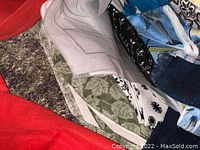 Photo showing pieces of fabric with leaf prints, black and white designs, abstract and floral patterns, blue fabric, and other assorted colors in a bag.