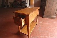 Side view of the solid oak side table showing drawer partially open and lower shelf.