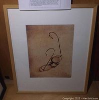 Framed and matted sepia photograph showing vintage eyeglasses with wire temples, with a view of the whole frame.