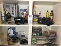 Shelf with Black & Decker drill in box, drill bit set, various small hand tools and household items including staples, tape, and small hardware items