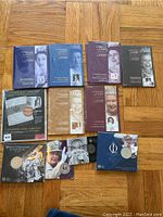 Photo showing the 6 hardcover volumes of Canada Post Diamond Jubilee Stamp Collections, featuring covers with various portraits of Queen Elizabeth II across decades, along with some duplicate volumes and a collection completion display.