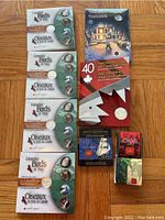 Overall layout: five sealed Birds of Prey sets on left; flag anniversary vertical folder with CD; Holiday Carols folder; two small cases at bottom right.