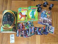Lot spread showing all items including Gumby and Pokey figures, Lord of the Rings Frodo figure, Batman and Robin figures, and superhero cards.