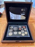 Overall view of the 2011 UK Royal Mint Executive Proof Set with coins in clear protective case, wooden display box open showing booklet and coins.