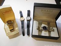 Four men's wristwatches including Caravelle by Bulova in original box, two leather band watches, and Bhagi Collection watch in original box