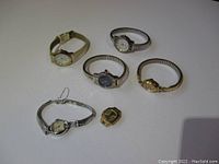 Overview of six assorted women's wristwatches showing various metal bands and face shapes