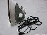 Side view of the Black and Decker First Impressions steam iron showing profile and attached power cord coiled beside it on a white surface.