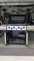 Front view of Broil King Sovereign XL Propane Barbecue Grill with opened lower cabinet showing storage and propane tank space.