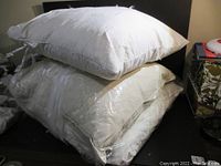 Stack of three white cushions on a chair, showing general condition and fabric texture of cushions.