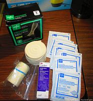 Photo showing Medigrip elastic tubular band box, rolled elastic tubular band, 3M Cavilon cream tube, and individually packaged non-woven gauze sponges spread out on table.