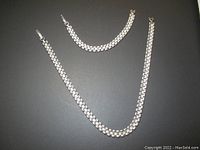 Silver tone box-link chain necklace and matching bracelet, displayed on flat surface