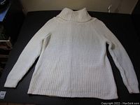 Front view of new cream women's sweater laid flat showing long sleeves and turtleneck collar