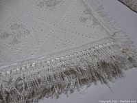 Close-up image of the bedspread's corner showing intricate pattern and fringed edge tassels.