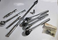 Multiple chrome ratchet handles and extensions, some branded Craftsman, laid out on a white surface.