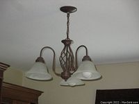 Full view of the vintage dark copper metal chandelier installed, showing three frosted veined glass bell shades and twisted basket center design.