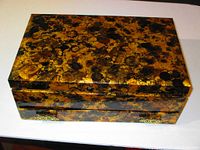 Top view of the rectangular jewelry box showing the mottled brown and black faux tortoiseshell finish with slight gloss and decorative metal corner accents.
