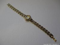 Full length view of the watch showing the entire band and face with gold electroplated raised dot pattern.