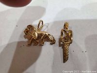 Lion and key pendants side by side on white background