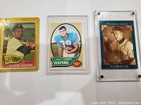 Front view of three sports cards: Elston Howard Yankees baseball card, Larry Csonka Dolphins football card, Cal Ripken Jr. Heritage Series baseball card in plastic cases.