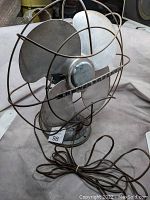 Side view of antique Westinghouse electric fan showing blades, wire guard, and power cord.