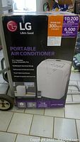 Front view of LG portable air conditioner box showing model LP1017WSR. Box highlights cooling capacity 10,200 BTU/hr, dehumidifying, fan operation, oscillating vent, remote control.