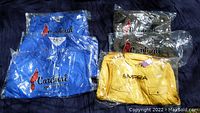 Six new men's outerwear pieces in plastic packaging: two blue Cardinal windbreakers size 2XL, one blue Cardinal windbreaker size L, two khaki Cardinal windbreakers size M, one yellow EMPRA vest size 2XL visible with logos and packaging intact.