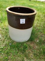 Photo of ceramic planter pot standing upright on grass outdoors, showing front view with label 85 attached.