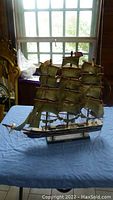 Full vintage model of the Cutty Sark sailing ship displayed on a table by a window, showing detailed sails and hull.