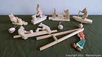 Full view of six wooden mechanical toy sculptures on a cloth surface showing the varied animals and figures in seated and standing positions with attached wooden balls and strings for mechanical movement.