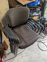 Stacked chairs showing checkered upholstery and black metal armrests and legs from side angle.