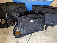 Three black laptop messenger bags displayed on floor, showing variety in size and design.