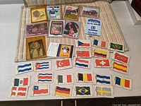 Top down view showing a variety of vintage trading cards and promotional items arranged on a surface including cards with cartoon characters, sports figures, and various flag patches.