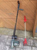 Full view of Black & Decker electric edger and Toro string trimmer standing against wood wall and stone floor.
