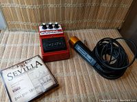 Lot showing Sevilla guitar strings box, red DOD FX 55C distortion pedal, and black Shure Brothers vintage microphone with attached cable.