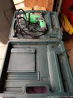Hitachi D10VH corded power drill inside green hard plastic carrying case with molded compartments for accessories.