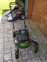 Front angled view of John Deere mower showing handle, front rotating wheels and engine cover.