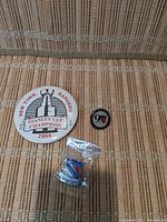 All four pins displayed on a beige woven surface: large 1994 Stanley Cup Champions button, 90th anniversary pin, blue Rangers logo pin in sealed bag, and smaller pins.