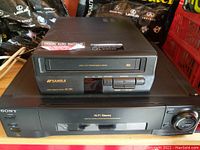 View of Sansui VCP1500 VCR player stacked on top of Sony SLV-770HF Hi-Fi Stereo VCR player, showing front and top sides of both units