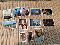 Photo of front sides of 11 Superman trading cards from Costa Rica, displayed on a beige surface. Cards are smaller than standard size, various character and action images.