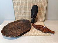 Photo showing the three items together: large carved tray, smaller bird carved tray, and hand carved ebony head sculpture
