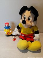 Photo showing all three items in the lot: large Mickey Mouse plush, small Mickey figurine, and Jelly Belly container