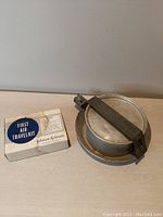 Photo of Johnson & Johnson First Aid Travel Kit with original box next to Kiffe Steel camping pot and lid