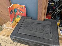 Closed black K'Nex storage case next to T-Rex instruction booklet